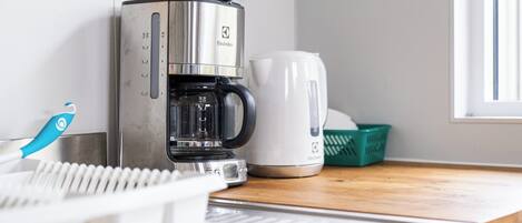 A coffee maker, a kettle, and a basket on a kitchen counter.