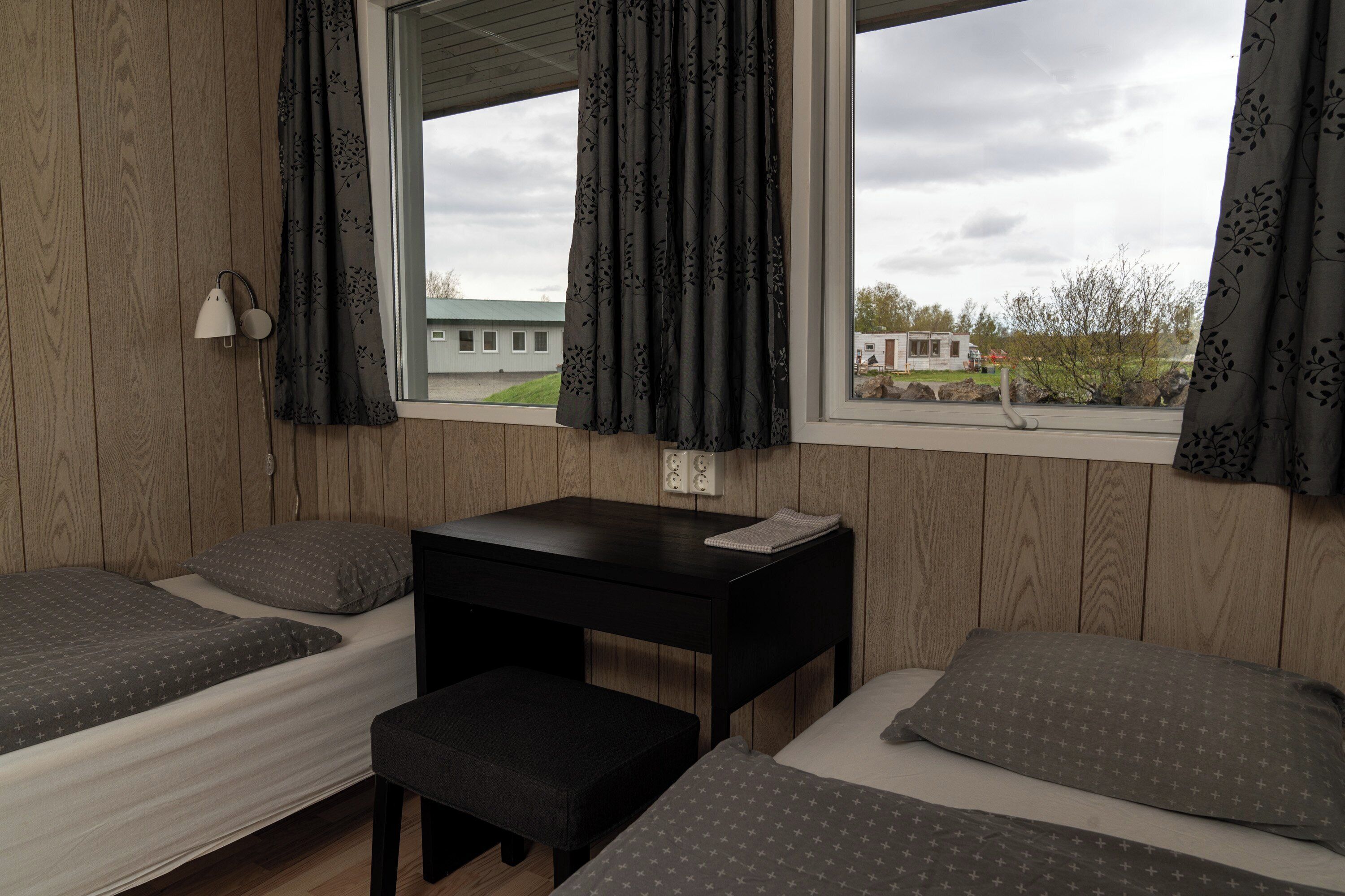 Een kamer met twee bedden, een bureau en een raam met gordijnen.