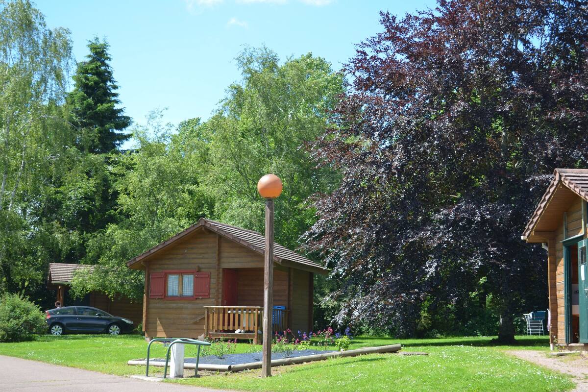 Eine Holzhütte mit Veranda, umgeben von üppiger Vegetation und Bäumen.