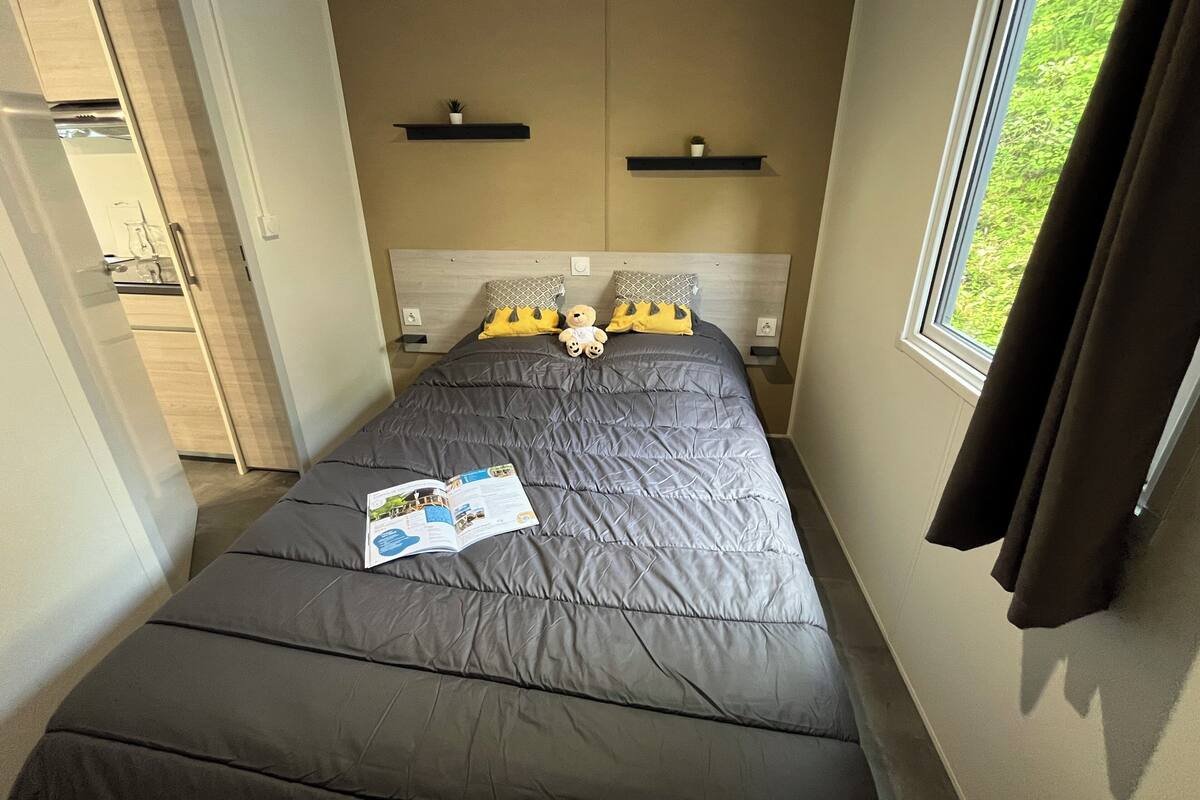 Ein Schlafzimmer mit Bett, Fenster, Tür und einem kleinen Tisch mit Pflanze.