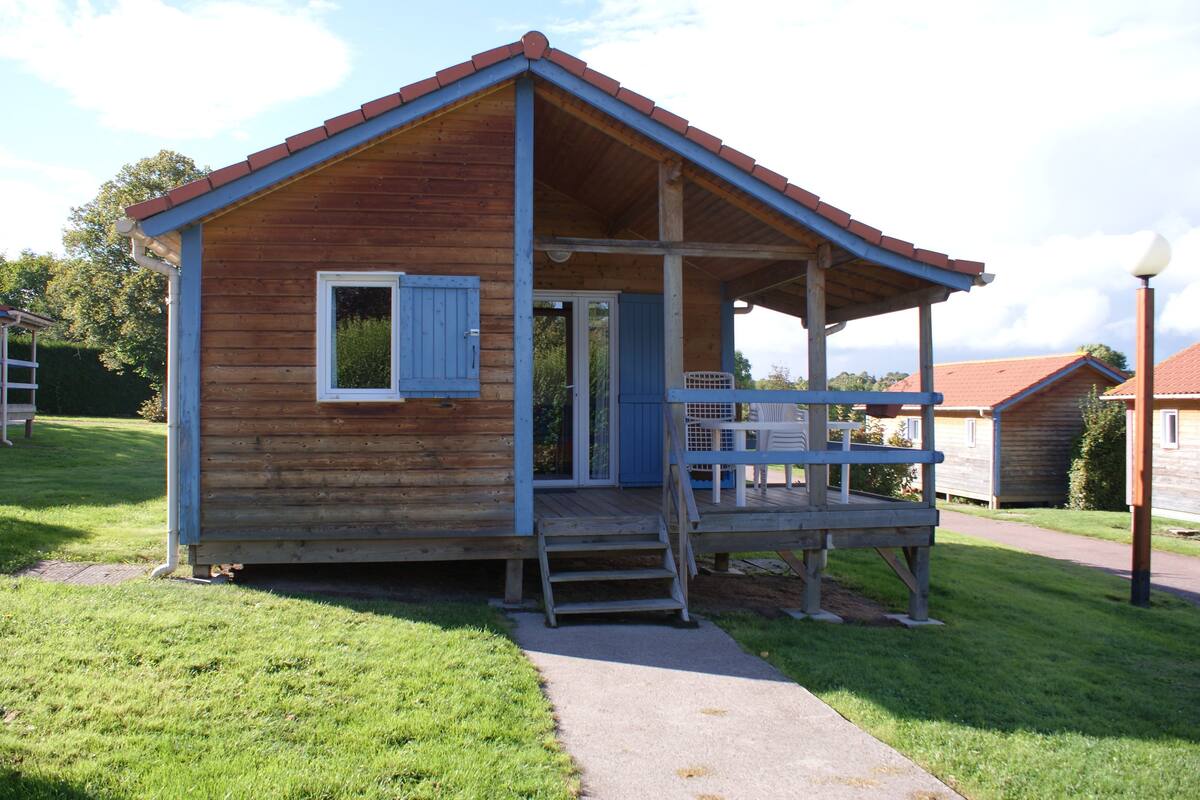 Eine kleine Holzhütte mit Veranda, Tür und Fenster.
