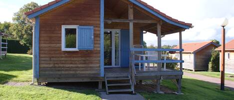 A small wooden cabin with a porch, a door, and a window.