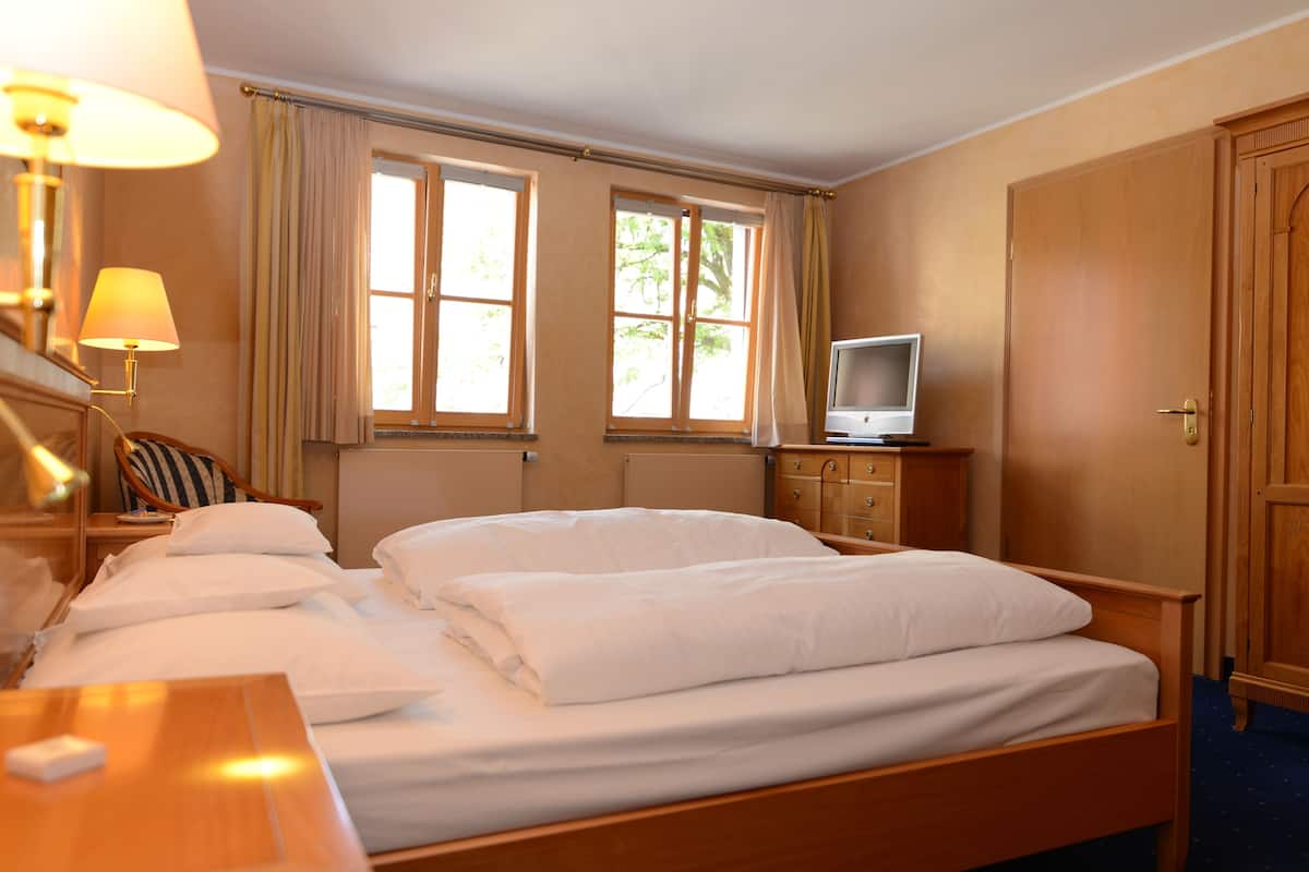 A hotel room with a bed, a TV, a desk, and a chair.