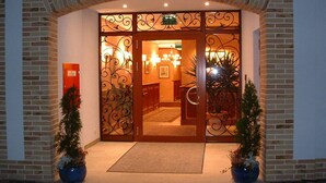 A hotel entrance with a brick facade, decorative iron gates, and potted plants. - Altstadt Hotel Bräu Wirt (Weiden in der Oberpfalz)