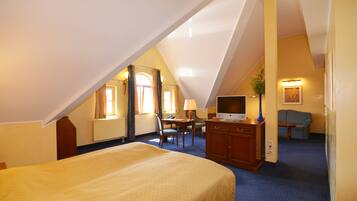 A hotel room with a large bed, a desk with a chair, a television, and a couch.
