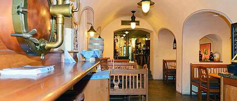 A bar area with wooden furniture, a copper barrel, and hanging lights.