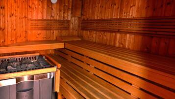 A sauna with wooden benches and a stone heating element.