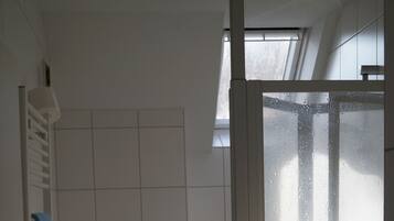 A bathroom with a toilet, a shower enclosure, and a window.
