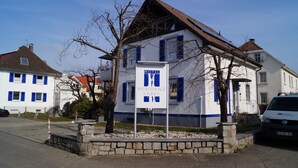 A white building with blue shutters, a sign indicating it is a motel, and a Volkswagen van parked in front. - Motel Residenz Labee (Weil am Rhein)
