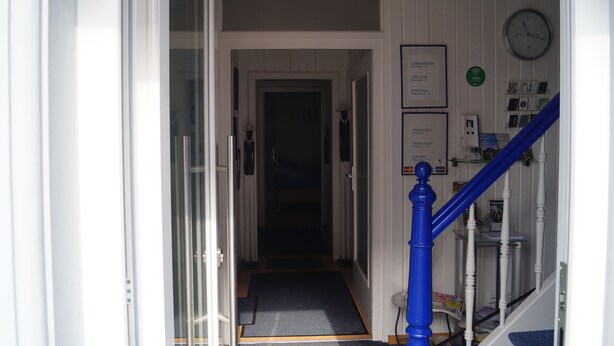 A hotel hallway with a staircase, a clock, and a sign listing room types. - Motel Residenz Labee (Weil am Rhein)