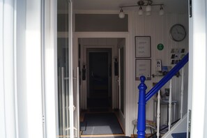 Un pasillo de hotel con una escalera, un reloj y un cartel que enumera los tipos de habitaciones.
