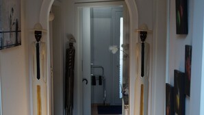 A hallway with a wooden floor, a black mat at the entrance, and a white door at the end. - Motel Residenz Labee (Weil am Rhein)