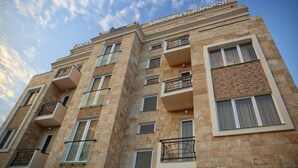 Un hotel de varios pisos con balcones, ventanas amplias y cielo despejado.