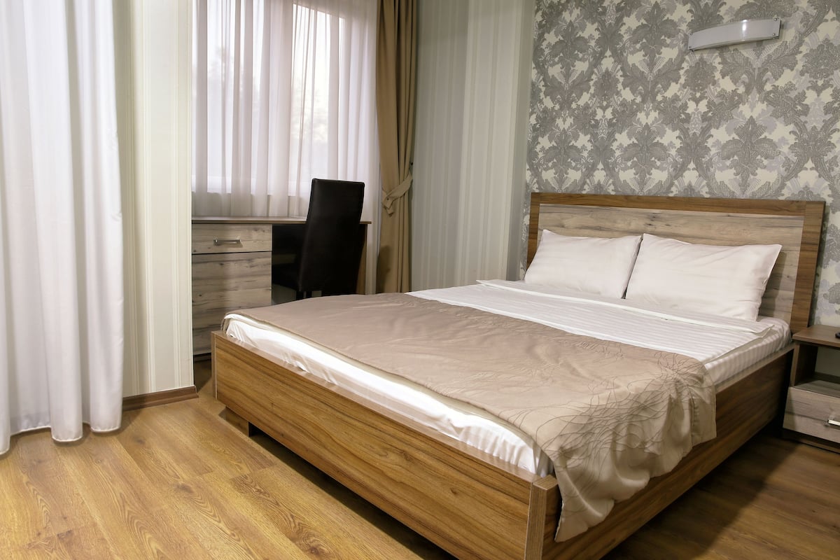 A bedroom with a wooden bed, a desk, and a chair.