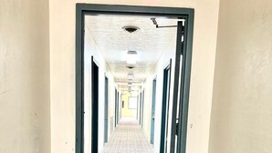 Un largo pasillo con suelo estampado, puertas a ambos lados y un techo con luminarias.