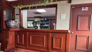 Una zona de recepción con un mostrador de madera, una alfombra roja y una puerta con un sticker de la bandera estadounidense.