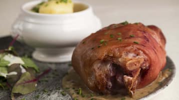 Un jambon rôti nappé de sauce, accompagné d’une salade, le tout servi sur une assiette.