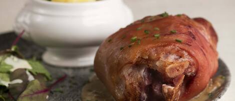 A roasted ham with gravy and a side salad on a plate.