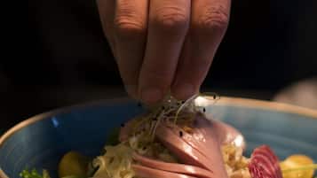 Una mano sosteniendo un tenedor sobre un tazón de ensalada con diversos vegetales y un trozo de carne.