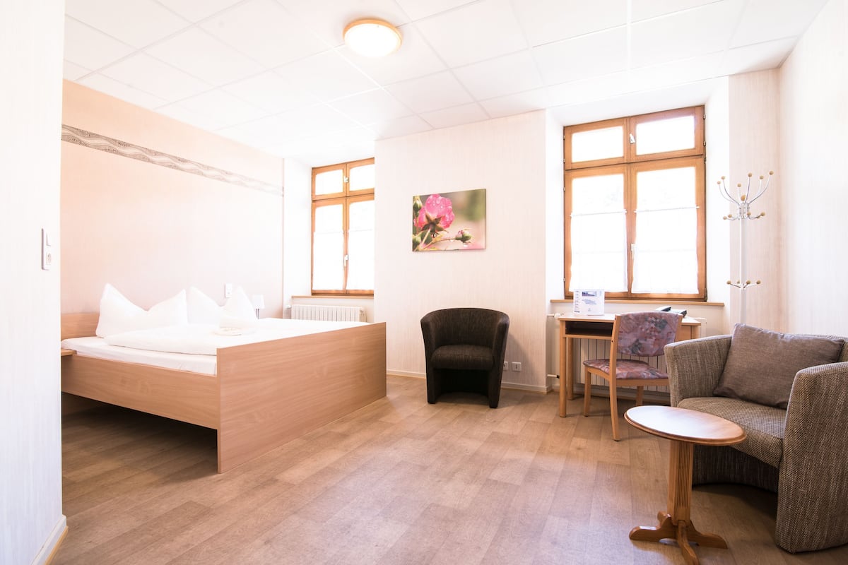 A room with a bed, a chair, a small table, and a sofa.