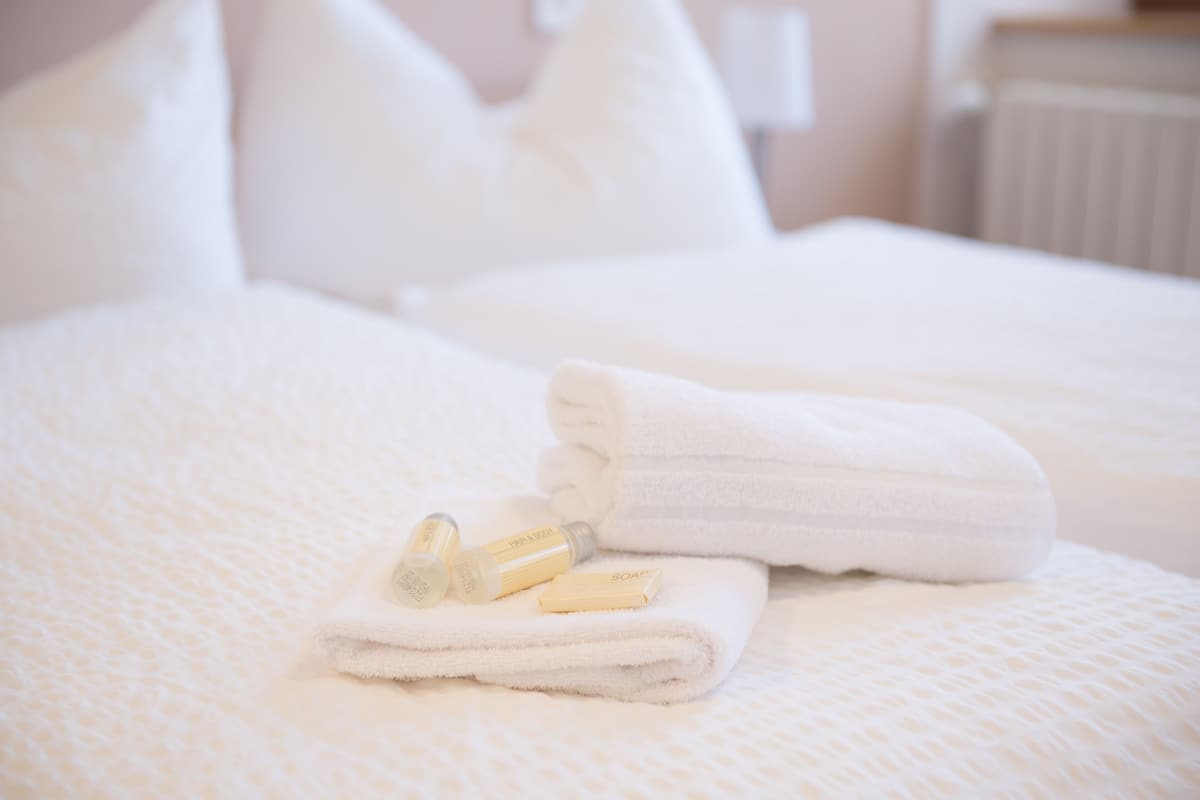 A neatly made bed with folded white towels and a bottle of soap.