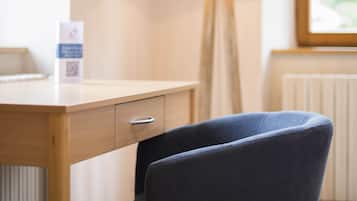 Ein Zimmer mit einem Holztisch, einem Stuhl, einer Lampe und einem Fenster.
