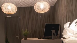 Zona de recepción de diseño moderno, con mostrador de recepción, dos lámparas colgantes, una computadora portátil y una silla.