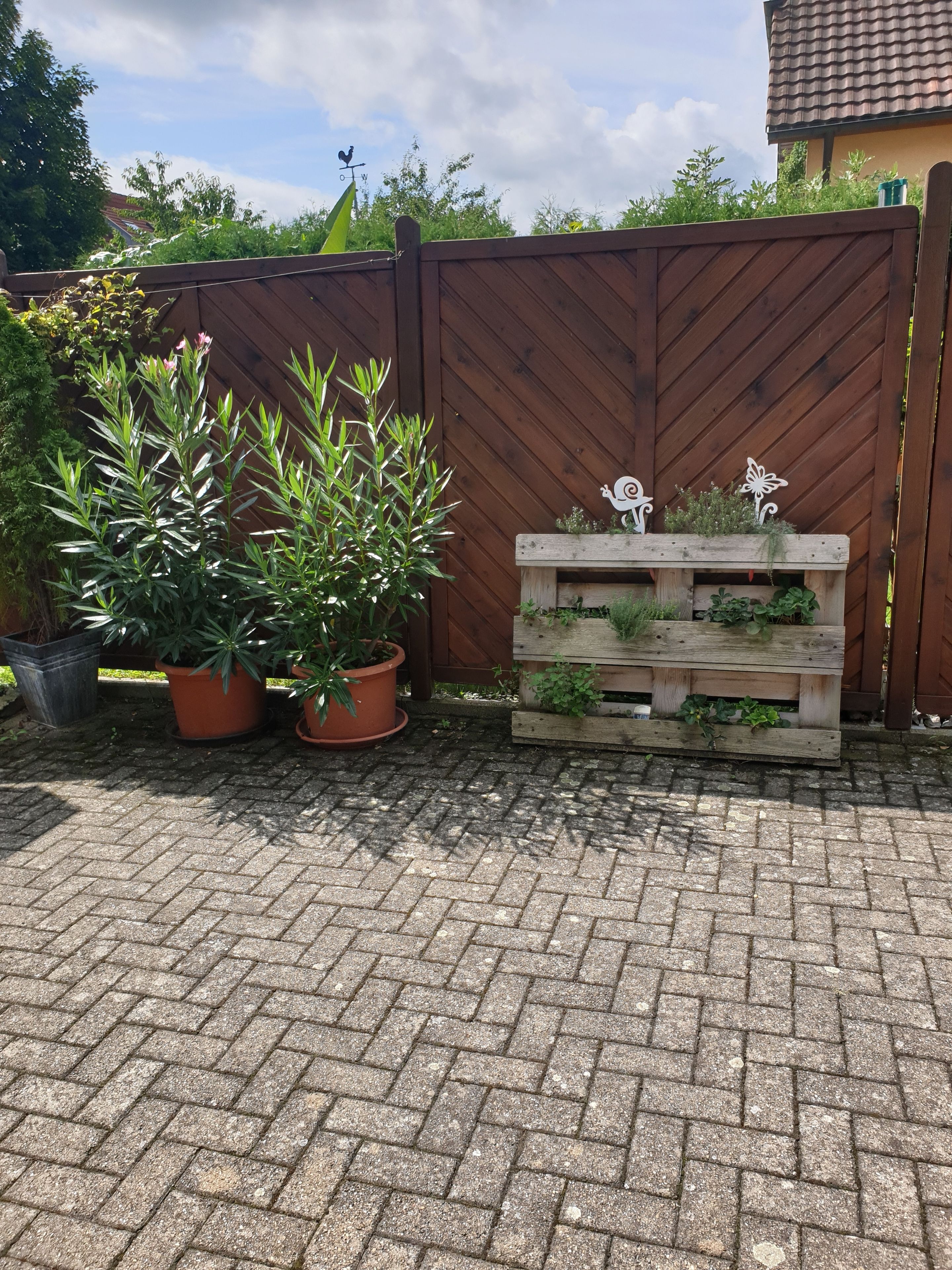 A wooden fence with a weather vane and a wooden planter box with plants.