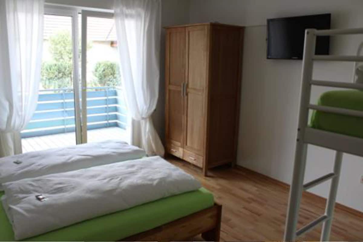 A room with a bed, a wardrobe, a TV, and a bunk bed.