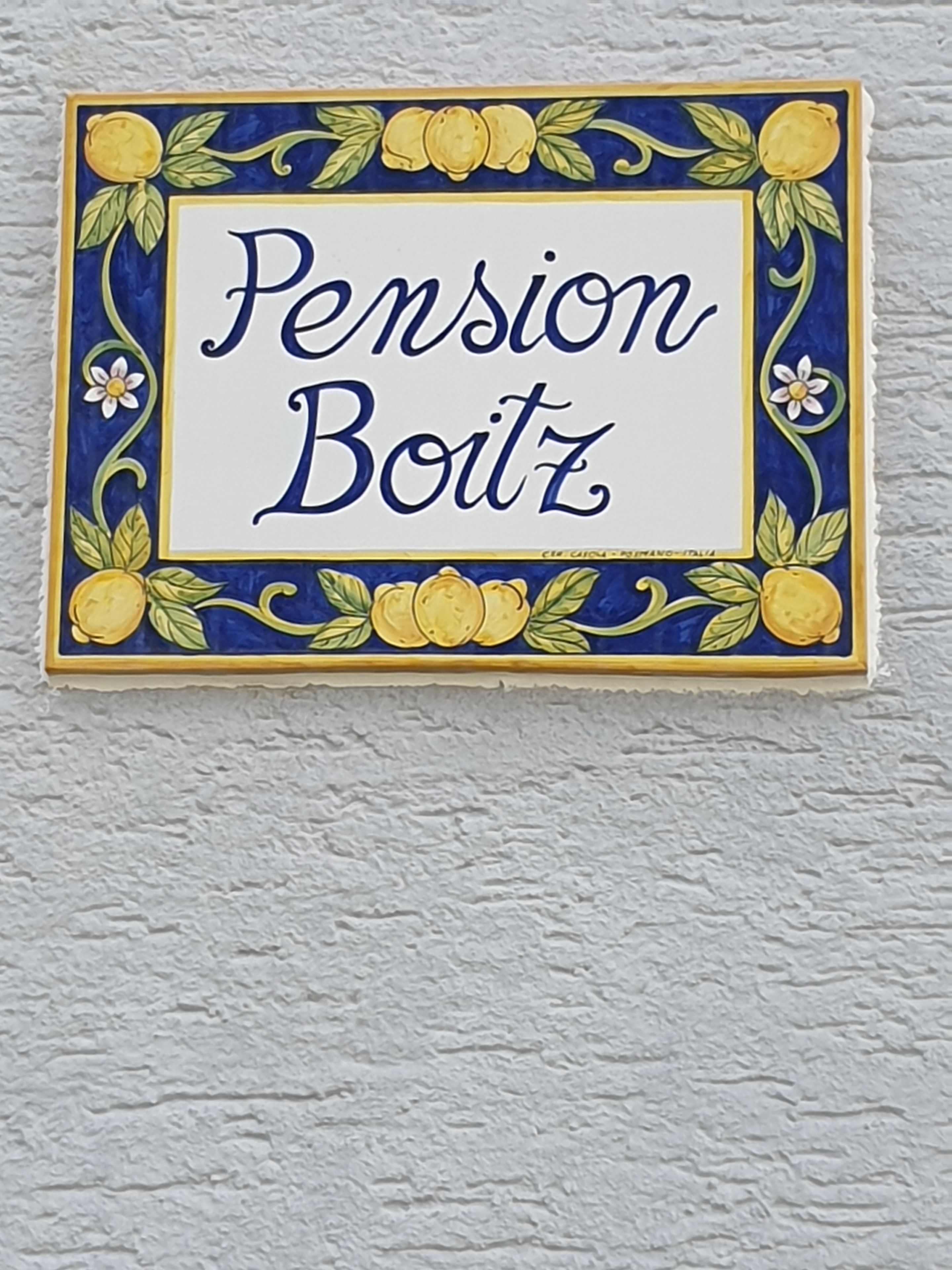 Uma placa decorativa com o texto 'Pension Boitz' envolto em um desenho floral.