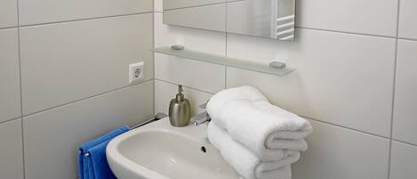 A bathroom with a white sink, a mirror, and a towel rack.