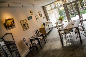A dining area with a marble table and chairs, framed artwork on the walls, and a view of the outdoors through large windows. - Art Home B&B (Carcassonne)