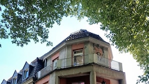 Un immeuble d’angle à la façade rouge, doté de nombreuses fenêtres et d’un balcon.