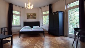 Une chambre à coucher comprenant un lit, un bureau, une chaise, une armoire et de grandes fenêtres.