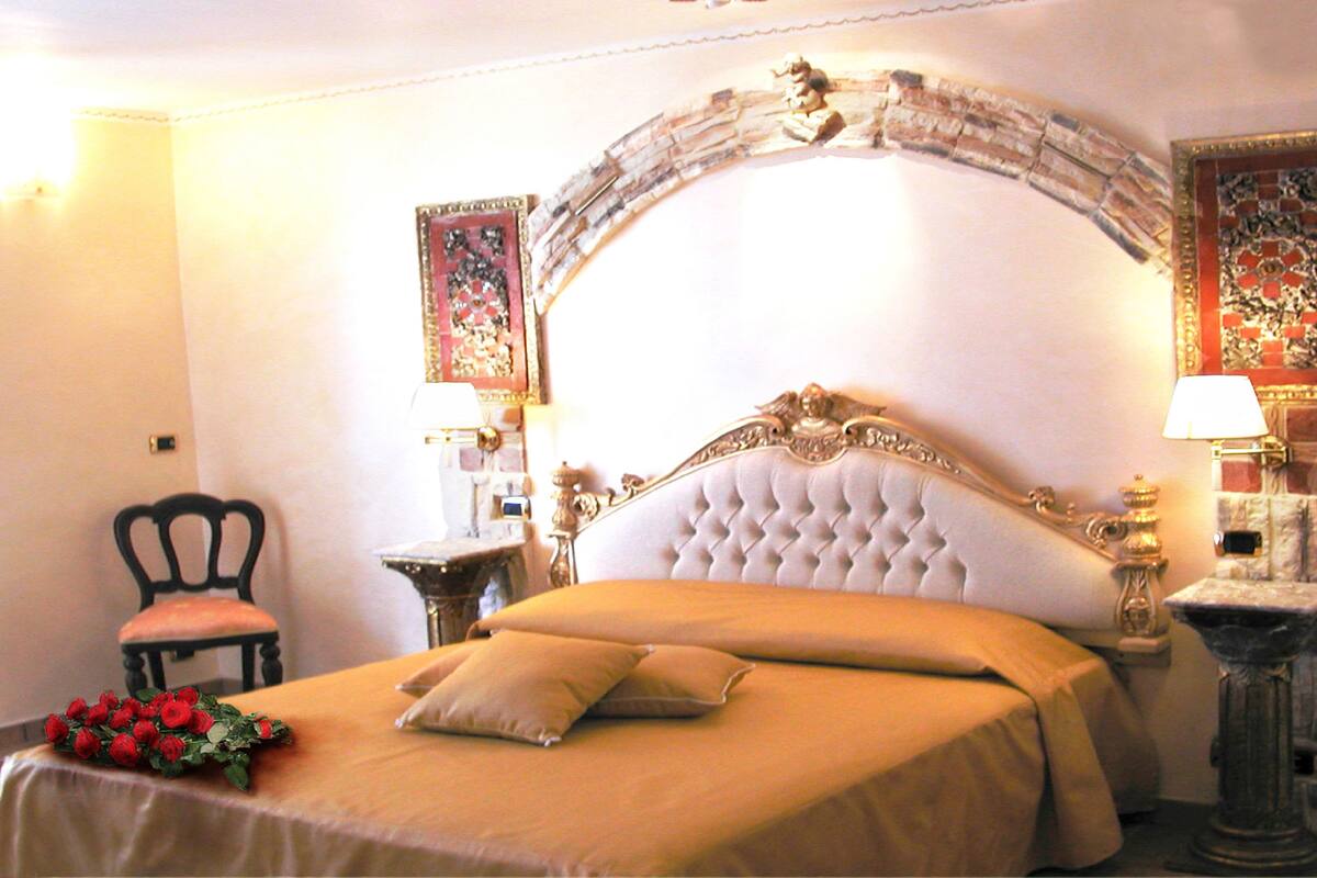 A hotel room with a large bed, a chair, and two nightstands with lamps.