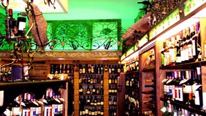 Un bar con estantes llenos de botellas y una pared decorativa verde.