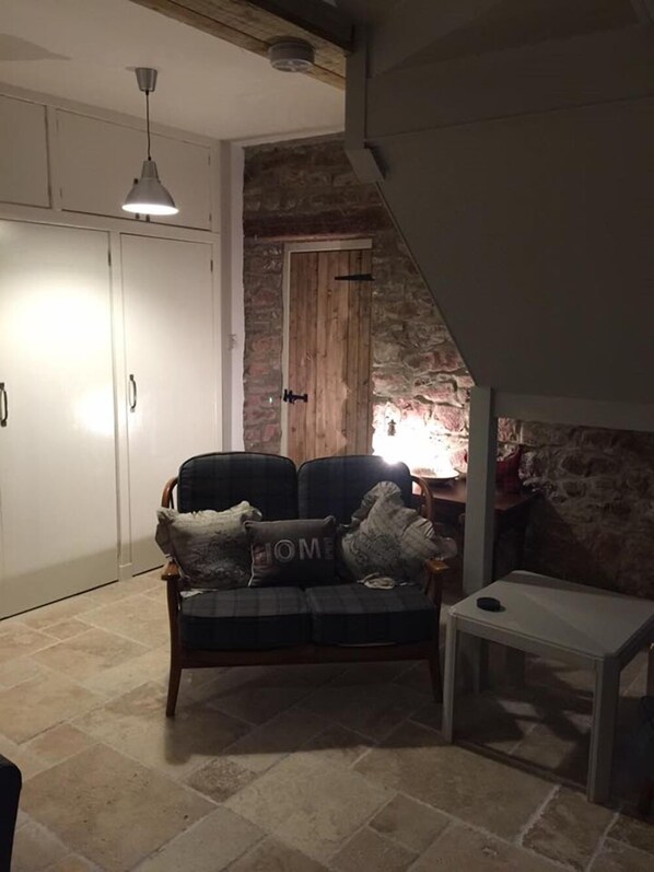 A cozy living room with a sofa, a small table, and a stone wall.