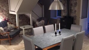 A dining area with a table and chairs, a pendant light, and a fireplace. - Dunruadh Cottage (Alexandria)