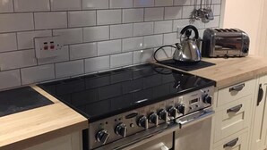 A kitchen with a black stove, a toaster, and a kettle on the countertop. - Dunruadh Cottage (Alexandria)