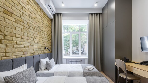 Une chambre d’hôtel avec deux lits, un bureau, une chaise et une télévision.
