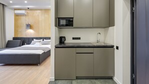 Une chambre moderne avec un grand lit et une petite cuisine équipée.