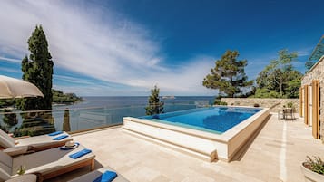 Una piscina al aire libre de temporada, sombrillas, tumbonas