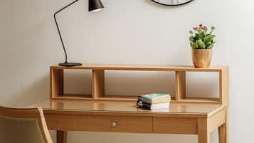 A wooden desk with a glass top, a black desk lamp, a potted plant, and a few books.