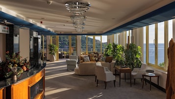 A spacious lounge area with a view of the sea, a reception desk, and modern furnishings.