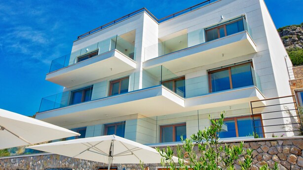 Un moderno edificio de varios pisos con balcones, ventanas amplias y fachada de piedra.