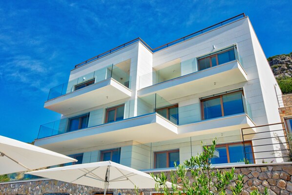A modern multi-story building with balconies, large windows, and a stone facade. - Villa Malo More (Dubrovnik)