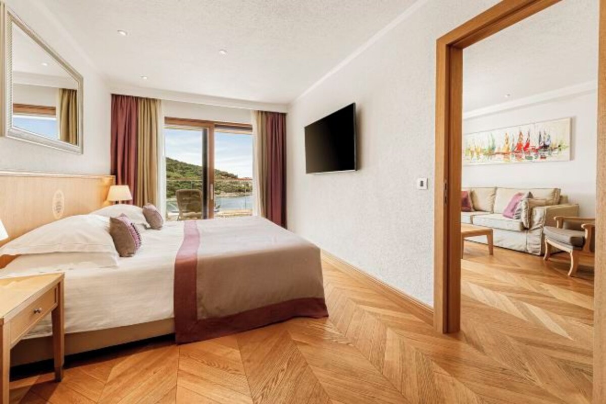 Quarto de hotel com cama, escrivaninha, televisão e vista para o exterior.
