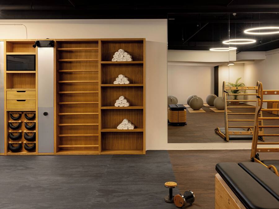 A modern gym with wooden equipment, a mirrored wall, and a ceiling with circular lights.
