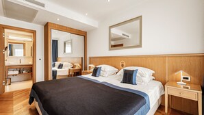 A hotel room with a large bed, a bedside table, a nightstand, a mirror, and a bathroom visible through an open door. - Villa Malo More (Dubrovnik)