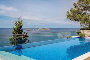 A clear blue pool with a glass barrier, overlooking a rocky coastline and the sea. - Villa Malo More (Dubrovnik)